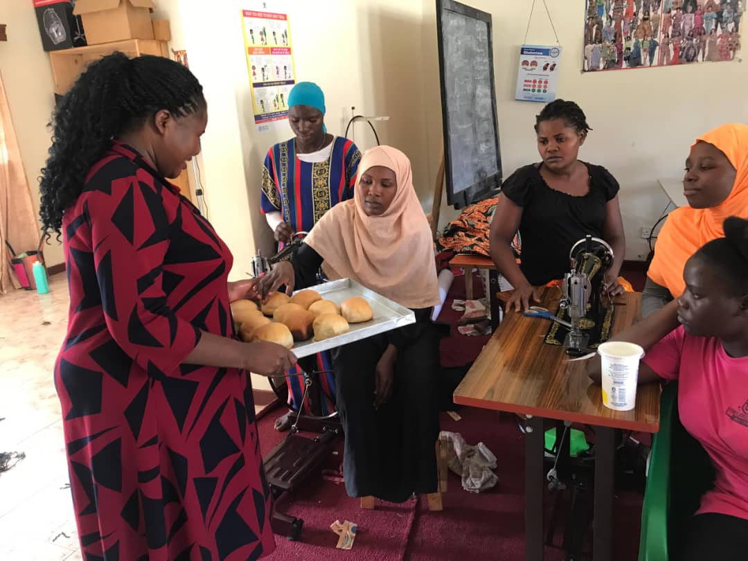 A trainer presenting a tray of freshly baked rolls to participants in the skills room